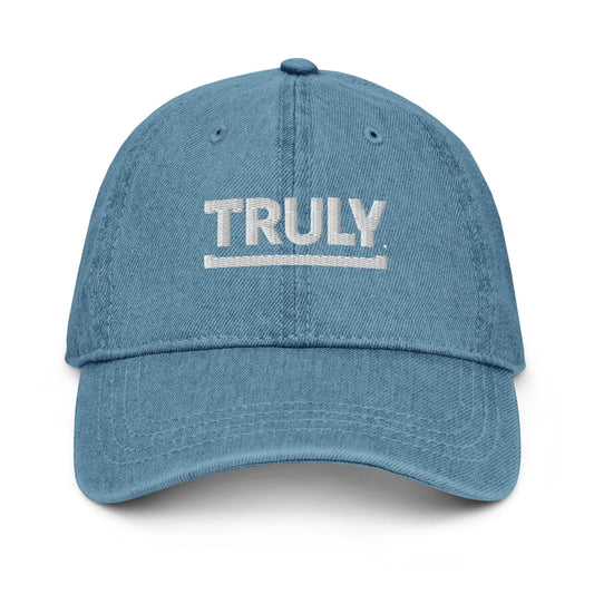 A light blue denim baseball cap with "TRULY" embroidered in white bold letters above a thin white underline on the front.