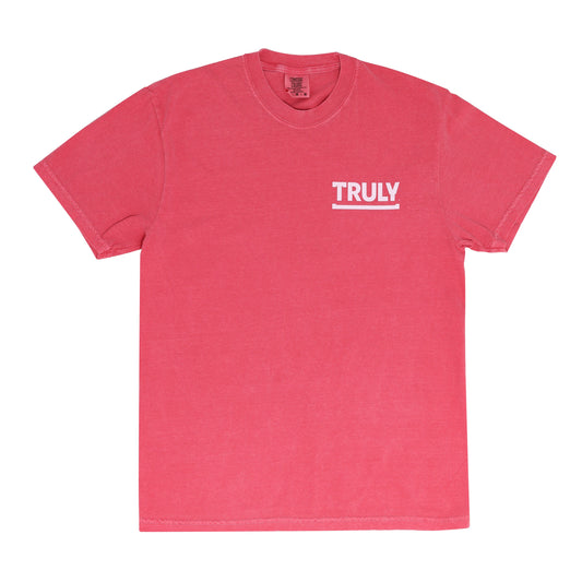 A pink short-sleeve mineral wash t-shirt featuring "TRULY" printed in white bold letters above a thin white underline on the left chest area.