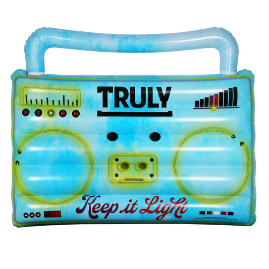 A large inflatable pool raft shaped like a light blue boombox with a distressed, watery pattern. It features yellow outlines of speakers, controls, a cassette tape slot, and the word "TRULY" in black bold letters, with "Keep it Light" in a darker red cursive below.