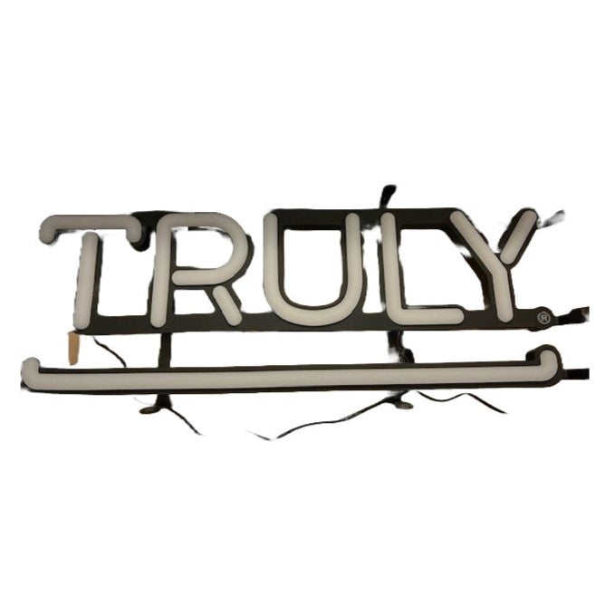 A white Truly-branded LED sign with the word "TRULY" illuminated in white, featuring black outlines and exposed wires.