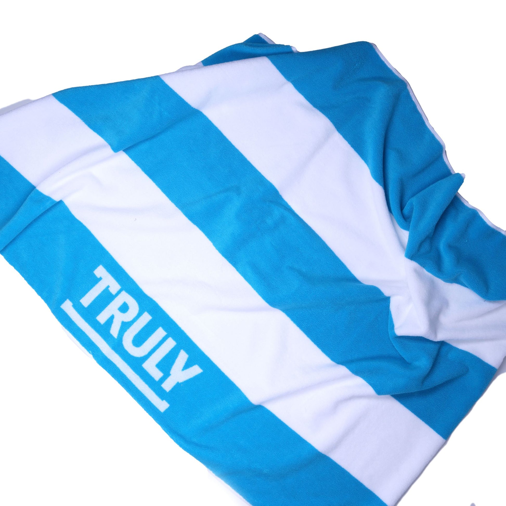 A sprawled out blue and white striped towel with the word "TRULY" printed across the blue stripe.