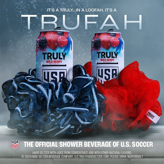 A promotional image with two wet Truly Wild Berry cans nestled in a dark blue loofah and a red loofah. Text at the top reads "IT'S A TRULY...IN A LOOFAH. IT'S A TRUFAH". At the bottom, "THE OFFICIAL SHOWER BEVERAGE OF U.S. SOCCER" is prominently displayed next to the U.S. Soccer logo.