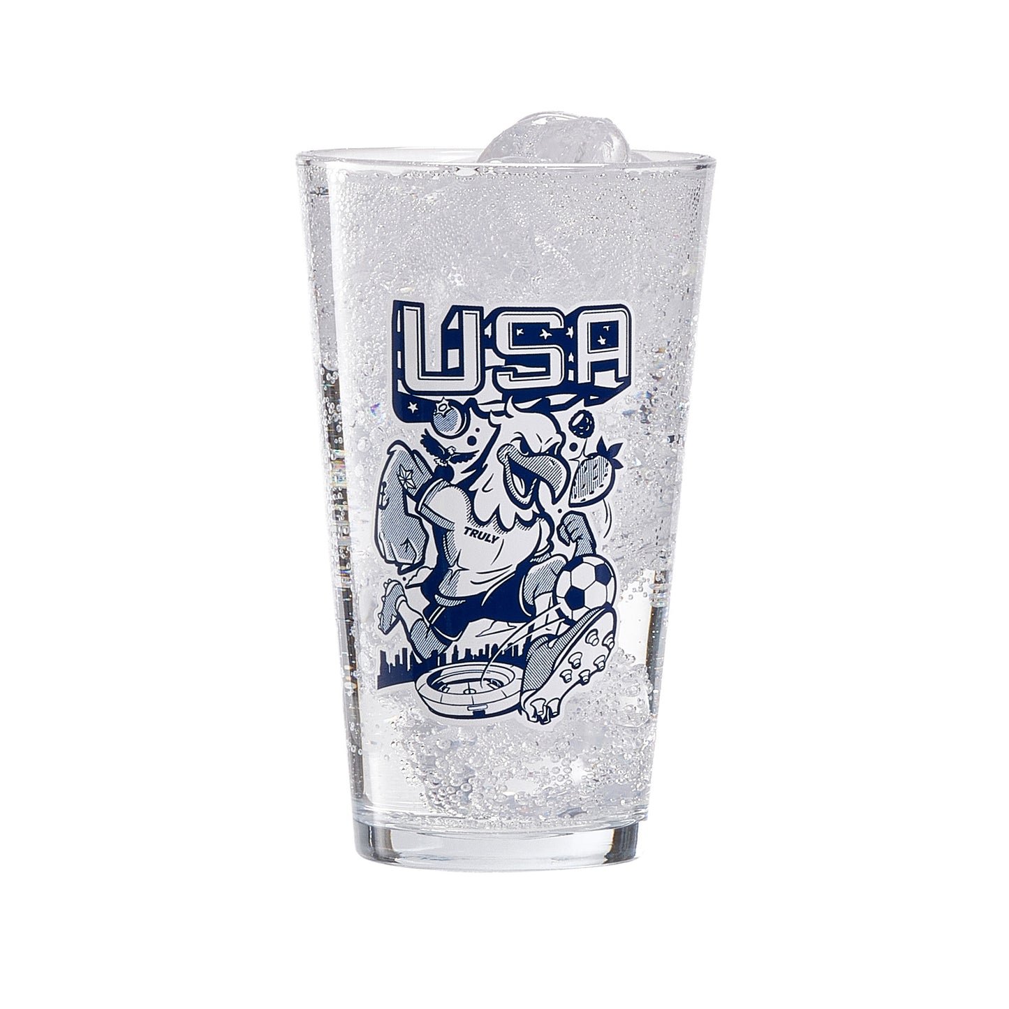 Clear pint glass filled with ice and a fizzy beverage, displaying a navy illustration with large “USA” text above a stylized eagle character graphic and decorative fruit elements. The design sits prominently on the front of the glass, creating a bold, eye‑catching barware piece.