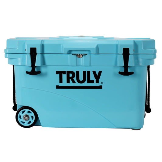 A light blue, possibly teal, portable cooler with "TRULY" in black text on the front. It has black latches, black rope handles, and wheels on one end.