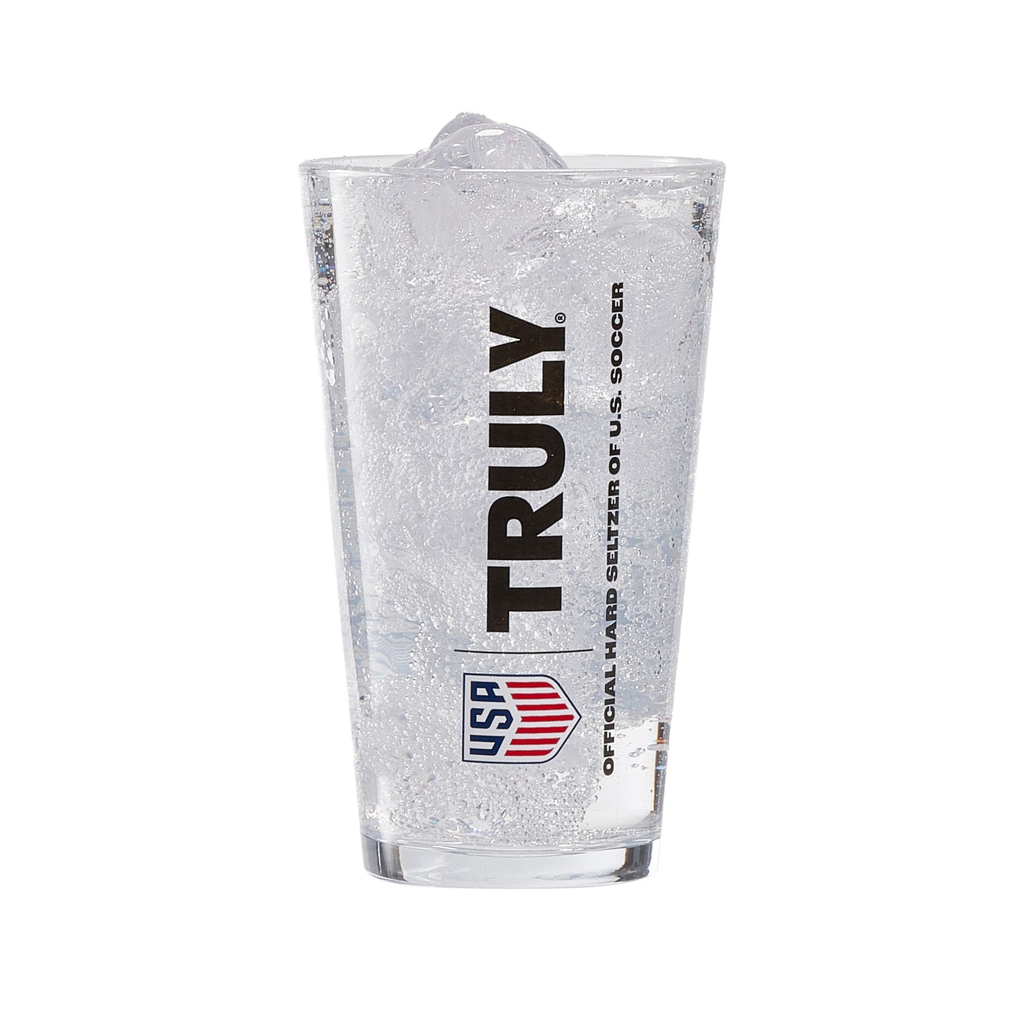 Clear pint glass filled with ice and a carbonated beverage, featuring vertical black “TRULY” branding and a red‑and‑blue shield‑style USA graphic. Beneath in smaller text is "Official Hard Seltzer of U.S. Soccer". Fine bubbles are visible throughout the drink, and the glass has a clean, modern shape suitable for beverages or barware.